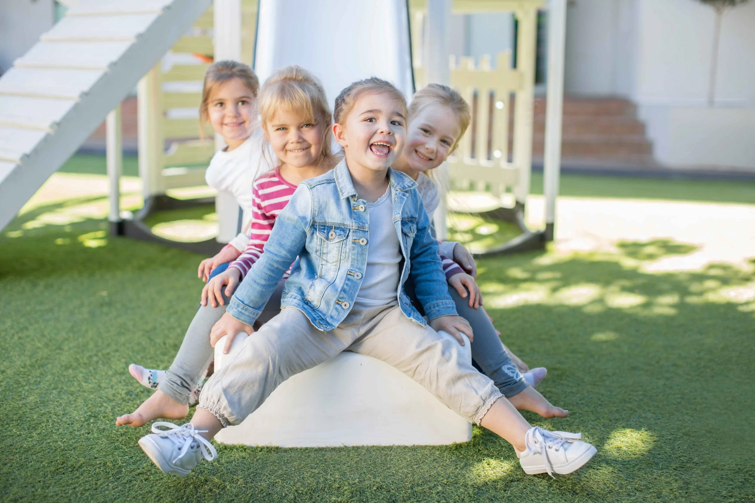 Kindergarten students laughing and playing outdoors on a sunny day