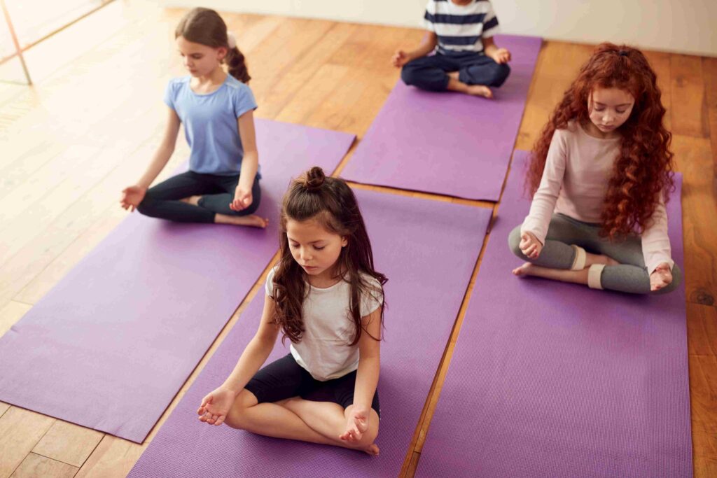 Kindergarten students practicing mindfulness and meditation on yoga mats