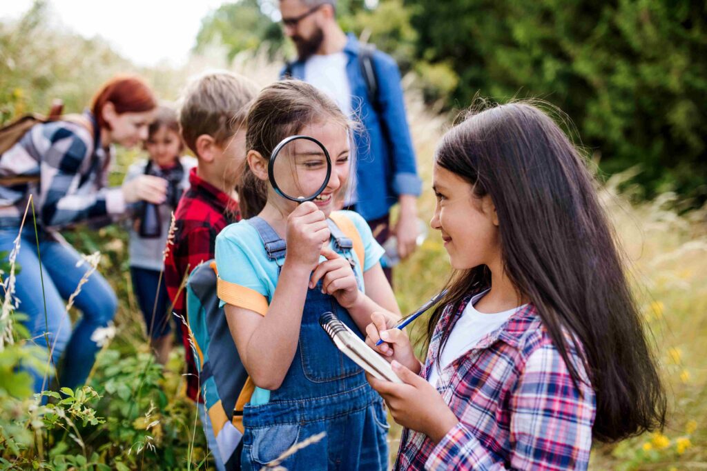 Students exploring nature with a magnifying glass during a teacher-led field trip